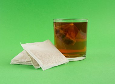 Bardakta bitki çayı kesesi, papatya çayı ve hiperikum ile sıcak su veya St. John 's Wort çay poşeti, tedavi amaçlı tıbbi içecek kupası, yeşil arka planda çay poşeti demleme süreci.