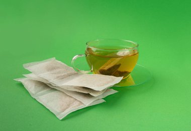 Fincanda bitki çayı kesesi, papatya çayı ve hiperikum ile sıcak su veya St. John 's Wort çay poşeti, tedavi amaçlı tıbbi içecek kupası, yeşil arka planda çay poşeti demleme süreci.