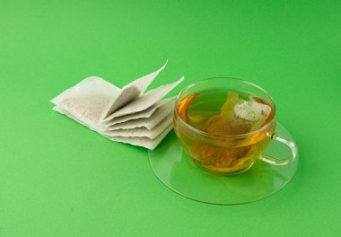 Fincanda bitki çayı kesesi, papatya çayı ve hiperikum ile sıcak su veya St. John 's Wort çay poşeti, tedavi amaçlı tıbbi içecek kupası, yeşil arka planda çay poşeti demleme süreci.