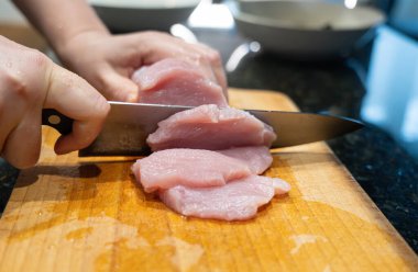 Çiğ hindi fileto nugget veya escalope için dilimleme, mutfak bıçağıyla et kesme, ev yapımı şnitzel pişirme süreci yakın çekim