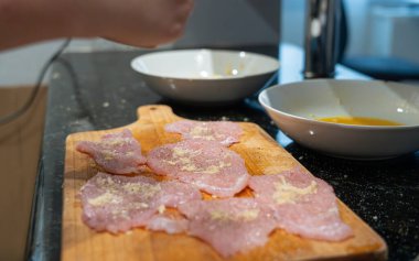 Şnitzel için yumuşatılmış et, ahşap biber değirmeni, hindi göğsü pişirme, ev yapımı şnitzel süreci.