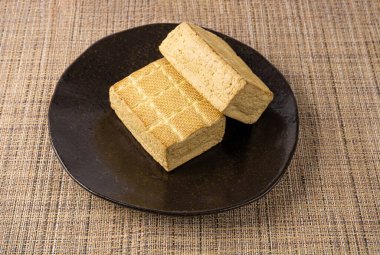 Tofu Peynir Bloğu, Siyah Tabakta Tütsülenmiş Vejetaryen Peynir Dilimi, Dilimlenmiş Soya Fasulyesi Kaymağı, Soya Proteini veya TSP Sağlıklı Et Analizi, Rustik Arkaplanda Tofu Peyniri