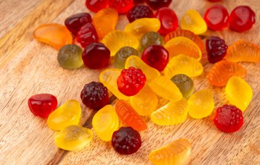 Meyveli şeker yığını yakın plan, vejetaryen marmelat çiğneme hapları, jelibon yığını, ahşap arka planda renkli jelatin şekerler.