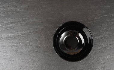 Siyah masa üstünde boş kase, koyu porselen tabak, karamsar tabak modeli, metin üst görünümü için fotokopi alanı olan mutfak afişi.