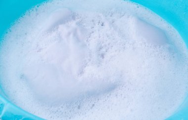 Çamaşırları mavi plastik bir leğenle yıkamak, ıslak beyaz bir bez, ev işi.