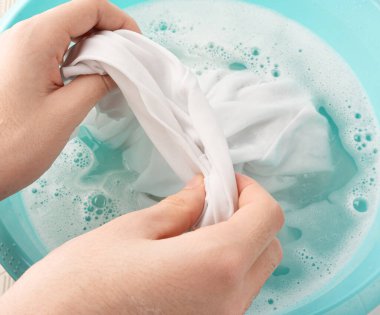 Çamaşırları mavi plastik bir leğenle yıkamak, ıslak beyaz bir bez, ev işi.