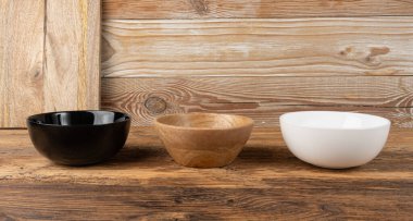 Masada üç boş kase, beyaz porselen, masa üstünde siyah ve ahşap tabaklar, kırsal tabak maketi, metin için fotokopi alanı olan eko biyo mutfak masaüstü afişi