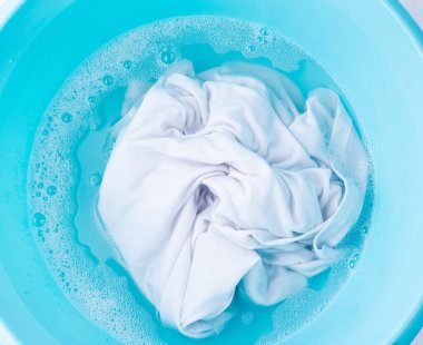Çamaşırları mavi plastik bir leğenle yıkamak, ıslak beyaz bir bez, ev işi.