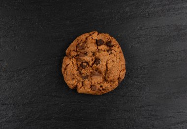 Çikolata parçalı kurabiyeler, Amerikan bisküvileri, kakaolu pasta, tatlı lokmalar fırın, siyah taştan arka planda yuvarlak pasta.