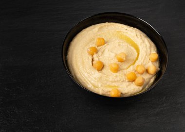 Kavanozda humus, ev yapımı sos, nohut humusu tahini sosu, orta doğu sosu, siyah arka planda Arap humusu.