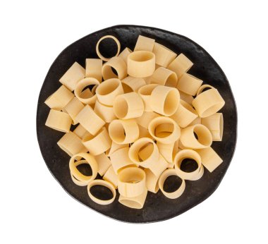 Çiğ Calamarata Big Pasta, Ev Yapımı Kuru Makarna, Pişmemiş İtalyan Yuvarlak Eriştesi, Beyaz Arkaplanda izole edilmiş Calamarata Makarna Halkaları. Siyah tabağın üstündeki mürekkep balığının görüntüsü
