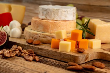 Peynir tabağı çeşitliliği, sarı, beyaz ve mavi gorgonzola tabağı, Munster, dört peynirli pano, çeşitli doğranmış süt ürünleri, ahşap üzerinde kokulu Fransız peyniri.
