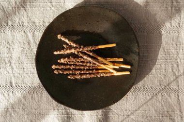 Siyah tabakta çikolatalı kurabiye çubukları, uzun çikolatalı pasta şekerlemeleri, Japon bisküvi tüpleri, tatlı kakao kremalı Grissini, Kore krakeri çubukları şekerlemeler