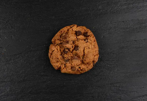 Çikolata parçalı kurabiyeler, Amerikan bisküvileri, kakaolu pasta, tatlı lokmalar fırın, siyah taştan arka planda yuvarlak pasta.