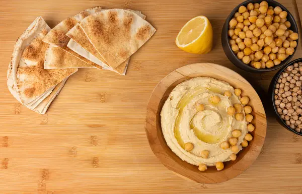 Tahta kasede humus, ev yapımı ev yapımı sos, nohut humus tahini sosu, orta doğu sosu, kırsal arka planda Arap humusu.