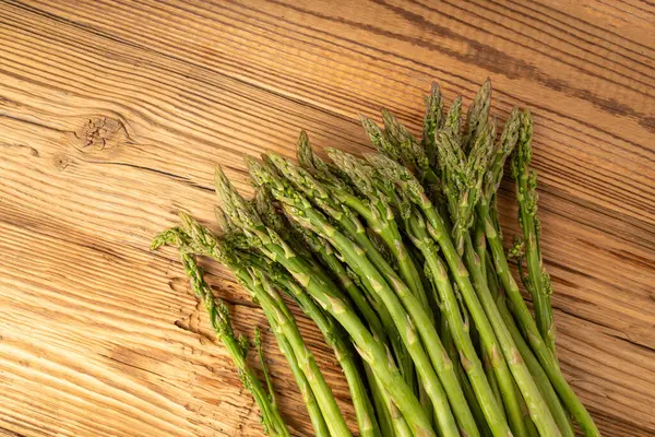 Ahşap Rustik Masaüstü 'nde bir demet Raw Garden kuşkonmazı. Taze Yeşil Bahar Sebzeleri, Yenilebilir Kuşkonmaz Resmi Yaylar Üst Kapak Kapağı