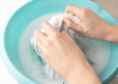Çamaşırları mavi plastik bir leğenle yıkamak, ıslak beyaz bir bez, ev işi.