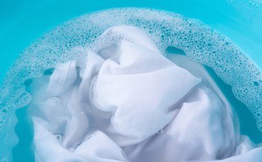 Çamaşırları mavi plastik bir leğenle yıkamak, ıslak beyaz bir bez, ev işi.