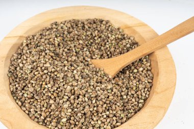 Ahşap kasedeki kenevir tohumları, kenevir taneleri, marihuana çekirdekleri, beyaz arka plandaki kenevir tohumları.
