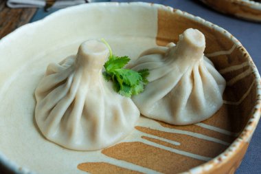 Gürcistan usulü khinkali ya da Çin usulü kıymalı. Geleneksel baharatlı Gürcü buğulama hamur köftesi, bir restoran tabağında servis edilen gamsum, momo, jiaozi, manti, pierogi veya wonton 'a benzer.