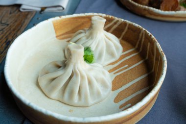 Gürcistan usulü khinkali ya da Çin usulü kıymalı. Geleneksel baharatlı Gürcü buğulama hamur köftesi, bir restoran tabağında servis edilen gamsum, momo, jiaozi, manti, pierogi veya wonton 'a benzer.