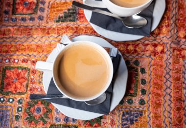 Hint restoranındaki bir masada iki beyaz fincan Masala çayı. İki üst düzey insanın iş görüşmesi sırasında.