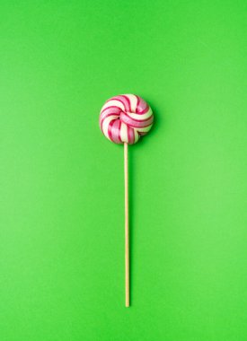 Renkli lolipop, çubukta sarmal şeker, renkli çizgili lolipop, yuvarlak meyveli karamel, çok renkli şekerleme, yeşil arka planda daire lolipop, metin için kopyalama alanı