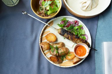 Gürcistan lula kebap tabağı. Barbekü şiş, geleneksel barbekü tabağı fırında patates ve salata. Izgara souvlaki, kıyma kebap, sofrada koyun eti lula, şişte ızgara kuzu.