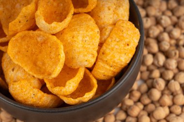 Humus nohut cipsleri yakın plan, cips yığını, makro portakal çerezi, kızarmış organik bakla gevreği, bulanık arka planda siyah kasede garbanzo fasulyesi atıştırmalıkları.