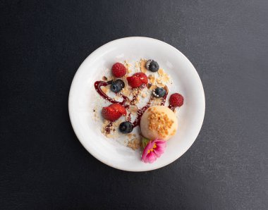 Meyveli mochi pirinç keki, beyaz daifuku, Japon geleneksel tatlısı, kremalı ve anko dolgulu yuvarlak wagashi, çilekli Asya şekeri, yaban mersini ve siyah arka planda çiçek.