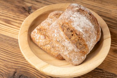 Kahverengi çavdar ekmeği, kare glütensiz ekmek, taze pişmiş tam tahıllı sağlıklı kahvaltı ekmeği, sade ahşap arka planda.