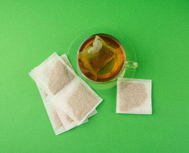 Fincanda bitki çayı kesesi, papatya çayı ve hiperikum ile sıcak su veya St. John 's Wort çay poşeti, tedavi amaçlı tıbbi içecek kupası, yeşil arka planda demleme işlemi