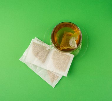 Fincanda bitki çayı kesesi, papatya çayı ve hiperikum ile sıcak su veya St. John 's Wort çay poşeti, tedavi amaçlı tıbbi içecek kupası, yeşil arka planda demleme işlemi