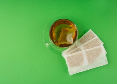 Fincanda bitki çayı kesesi, papatya çayı ve hiperikum ile sıcak su veya St. John 's Wort çay poşeti, tedavi amaçlı tıbbi içecek kupası, yeşil arka planda demleme işlemi