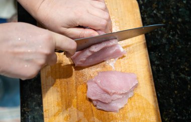 Çiğ hindi fileto nugget veya escalope için dilimleme, mutfak bıçağıyla et kesme, ev yapımı şnitzel pişirme süreci yakın çekim