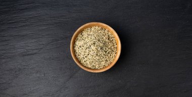 Kabuklu kenevir tohumları ahşap kasede, soyulmuş kenevir taneleri, kabuksuz marihuana çekirdekleri, siyah arka plan görünümlü yağ protein keneviri çekirdekleri
