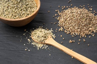 Kabuklu kenevir tohumları, soyulmuş kenevir taneleri, kabuksuz marihuana çekirdekleri, siyah arka planda yağlı protein kenevir tohumları.