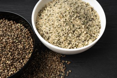 Kabuklu kenevir tohumları, soyulmuş kenevir taneleri, kabuksuz marihuana çekirdekleri, siyah arka planda yağlı protein kenevir tohumları.