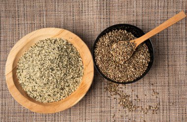 Kabuklu kenevir tohumları ahşap kasede, soyulmuş kenevir taneleri, kabuksuz marihuana çekirdekleri, ahşap arka planda yağ protein keneviri yığını.