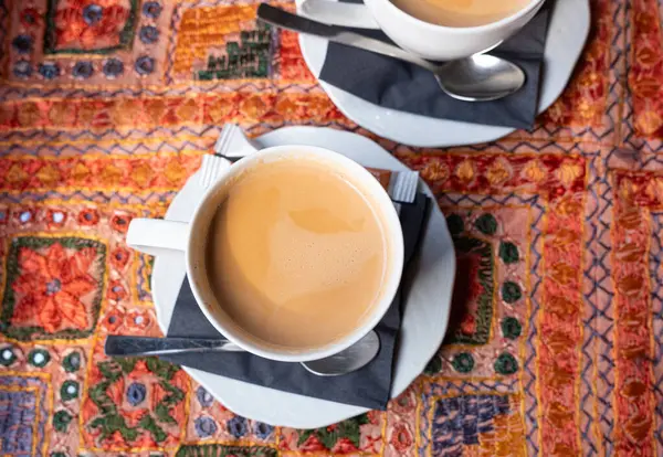 Hint restoranındaki bir masada iki beyaz fincan Masala çayı. İki üst düzey insanın iş görüşmesi sırasında.