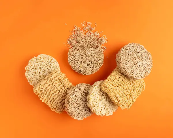 Çeşit çeşit Çiğ Erişte, Kupa 'da Kuru Yuvarlak Ramen Eriştesi, Farklı Pişmemiş Kore Vermicelli, Hızlı Çin Buğday Makarnası, Turuncu Arka plan Üst Görünüm' de Anında Makarna Karışımı