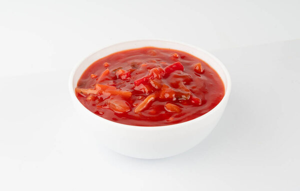 Томатный соус с овощами изолированный, красный сладкий и кислый соус маринара макароны, мексиканский мазок макароны с ананасом, лук, морковь, перец, бамбуковые побеги и травы в миске на белом фоне