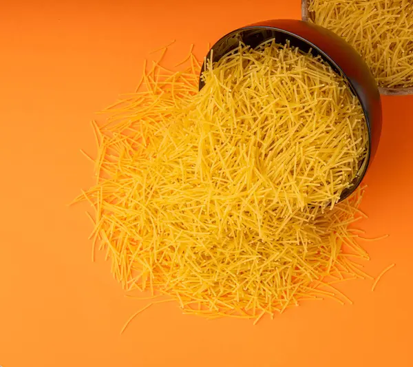 Turuncu arka planda çiğ vermicelli, yuvarlak altın çorba makarna, dağınık ev yapımı erişte, ince makarna, siyah kasede İtalyan sarısı filini makarna.