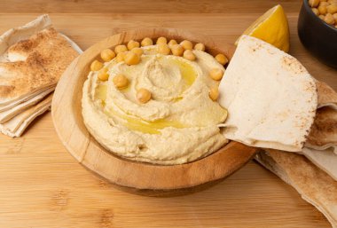 Tahta kasede humus, ev yapımı ev yapımı sos, nohut humus tahini sosu, orta doğu sosu, kırsal arka planda Arap humusu.
