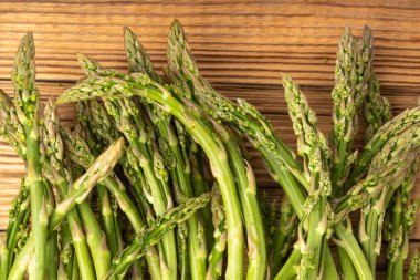 Ahşap Rustik Masaüstü 'nde bir demet Raw Garden kuşkonmazı. Taze Yeşil Bahar Sebzeleri, Yenilebilir Kuşkonmaz Resmi Yaylar Üst Kapak Kapağı