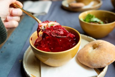 Borş çorbası ya da kase içinde borş, Ukrayna pancar çorbası. Ekşi kremalı ve yeşillikli kırmızı sebze çorbası. Restoran masasında sağlıklı Doğu Avrupa yemeği.