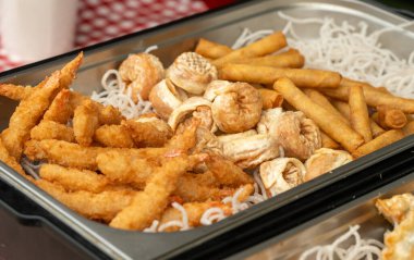 Kızarmış deniz ürünleri, kalamar halkaları, gevrek gyoza köfteleri, karidesler ve börekler. Asya büfesi, sağlıksız sokak yemekleri.