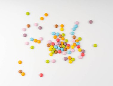 Dağınık küçük şekerler izole edilmiş. Renkli sürahiler, çok renkli çikolata düğmeleri, çeşitli dragee koleksiyonu, beyaz arka planda gökkuşağı şekerlemeleri