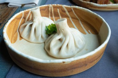 Gürcistan usulü khinkali ya da Çin usulü kıymalı. Geleneksel baharatlı Gürcü buğulama hamur köftesi, bir restoran tabağında servis edilen gamsum, momo, jiaozi, manti, pierogi veya wonton 'a benzer.