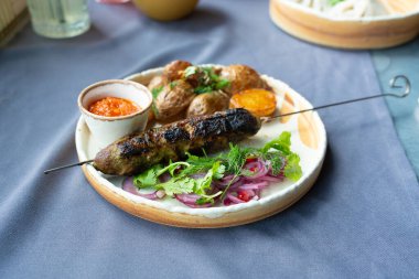 Gürcistan lula kebap tabağı. Barbekü şiş, geleneksel barbekü tabağı fırında patates ve salata. Izgara souvlaki, kıyma kebap, sofrada koyun eti lula, şişte ızgara kuzu.